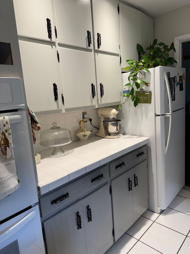2071 N Belsay Rd, Burton, MI 48509 - kitchen with freestanding refrigerator, refrigerator, backsplash, light tile patterned floors, and tile counters