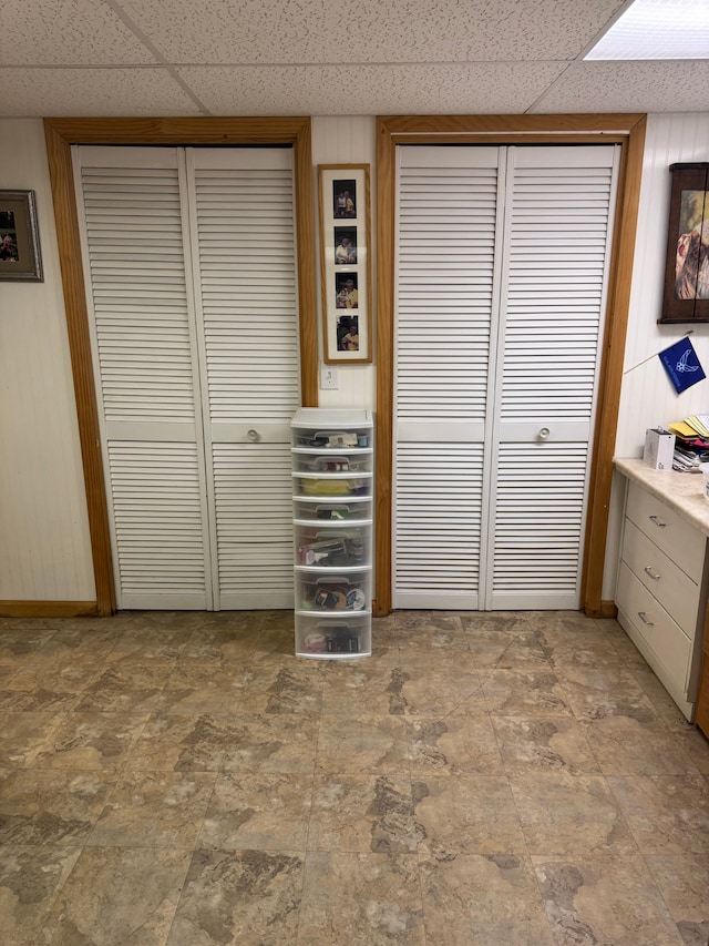 2071 N Belsay Rd, Burton, MI 48509 - unfurnished bedroom featuring two closets, a drop ceiling, wooden walls, and baseboards