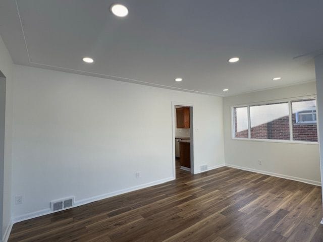 empty room with dark wood-type flooring, recessed lighting, and baseboards