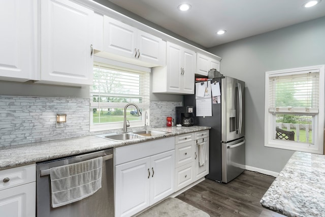 kitchen with stainless steel appliances, a sink, white cabinetry, light countertops, and tasteful backsplash
