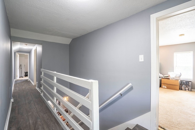 hallway featuring an upstairs landing, a textured ceiling, and baseboards