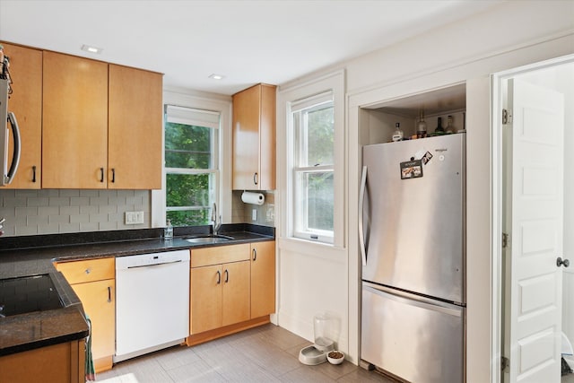 314 W Madison St, Ann Arbor, MI 48103 - kitchen with freestanding refrigerator, white dishwasher, a sink, backsplash, and dark countertops