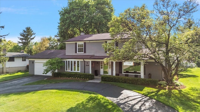 traditional home featuring asphalt driveway, a garage, covered porch, a front yard, and brick siding