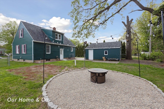 700 Scheurmann St, Essexville, MI 48732 - back of house featuring an outdoor fire pit, a chimney, an outdoor structure, a patio area, and roof with shingles