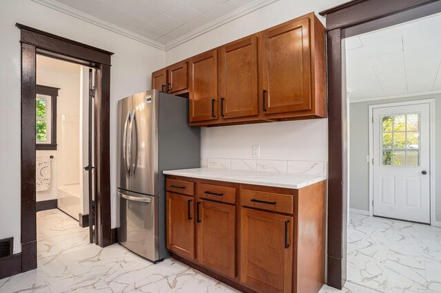 24 W Bernard St, Hartford, MI 49057 - kitchen with light marble finish floors, freestanding refrigerator, light countertops, brown cabinets, and crown molding