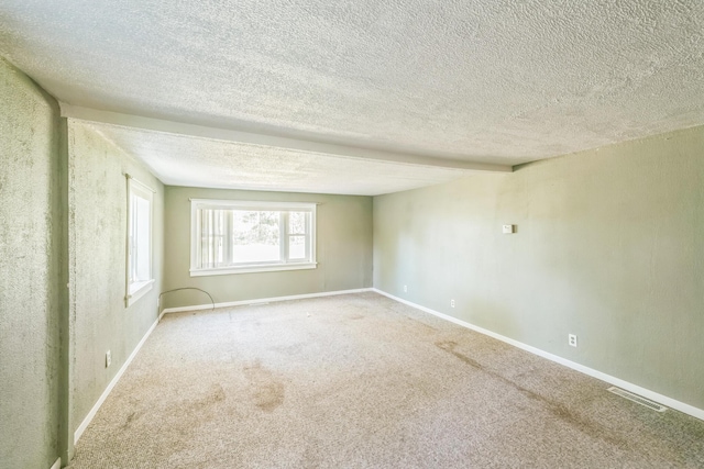 carpeted empty room featuring a textured ceiling and baseboards