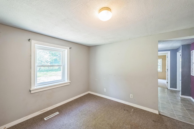 empty room with a textured ceiling, carpet floors, and baseboards
