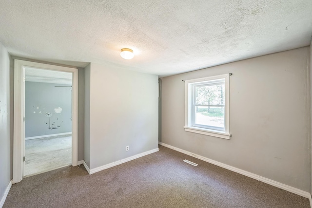 carpeted empty room with a textured ceiling and baseboards