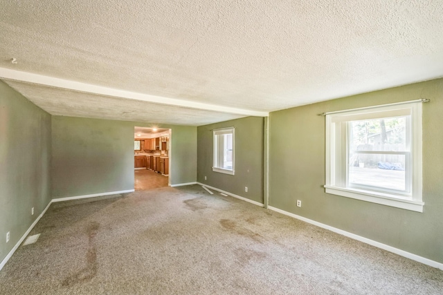 carpeted empty room featuring a textured ceiling and baseboards