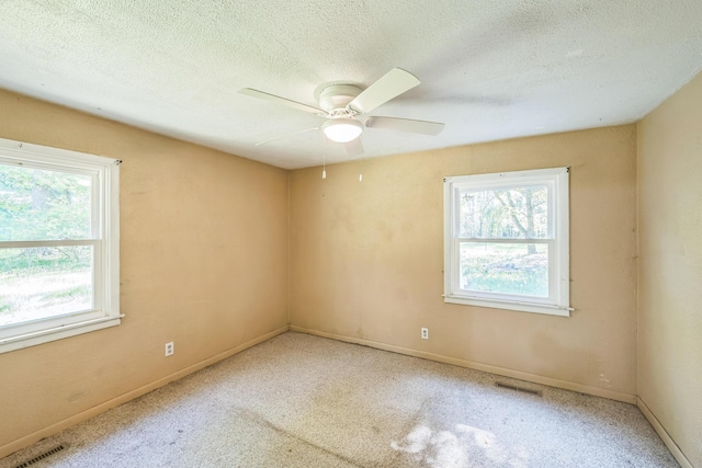 spare room with healthy amount of natural light, a textured ceiling, ceiling fan, and carpet
