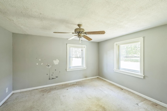 carpeted spare room featuring ceiling fan, a textured ceiling, and baseboards