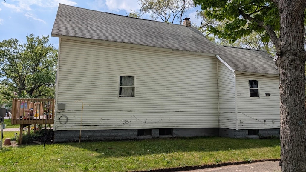 654 E Isabella Ave, Muskegon, MI 49442 - view of side of property with a lawn, roof with shingles, a deck, and a chimney