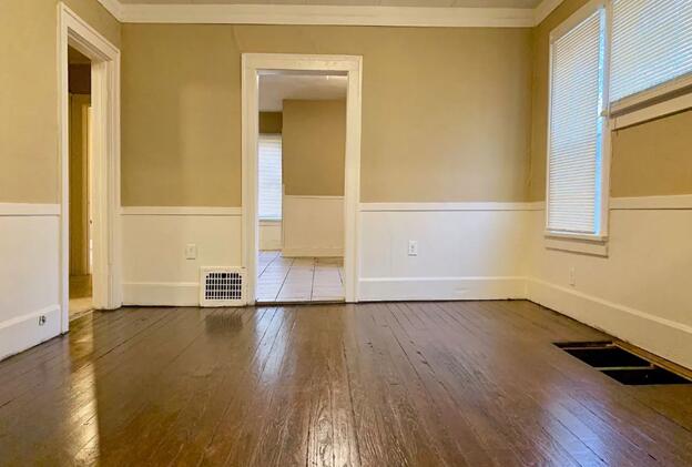 39 Iona Ave, Muskegon, MI 49442 - empty room with wood-type flooring, crown molding, plenty of natural light, a wainscoted wall, and baseboards