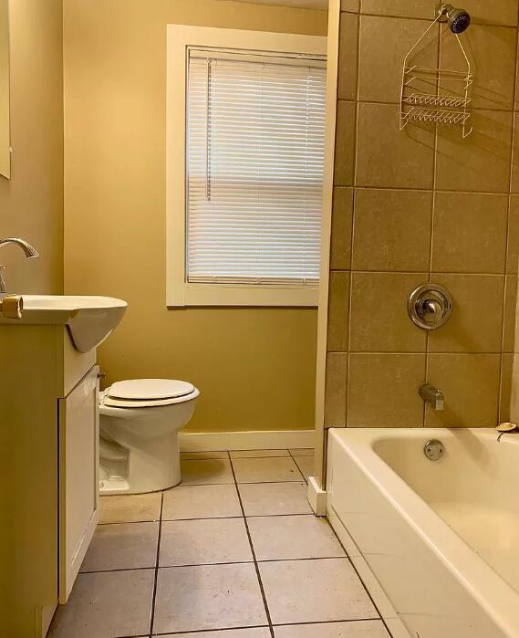 39 Iona Ave, Muskegon, MI 49442 - full bath with tile patterned floors, toilet, vanity, tub / shower combination, and baseboards