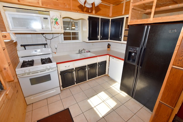 kitchen featuring white appliances, a sink, light tile patterned flooring, light countertops, and dark cabinets
