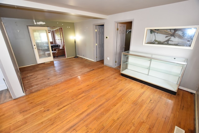 unfurnished bedroom featuring light wood-style flooring, a spacious closet, and baseboards