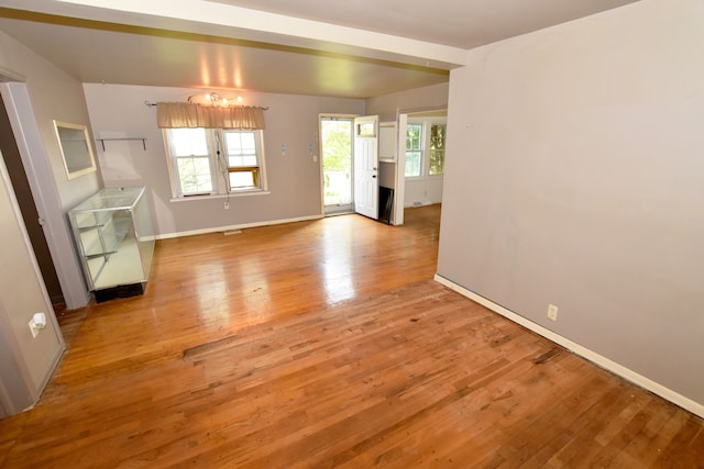 spare room featuring healthy amount of natural light, light wood-type flooring, and baseboards