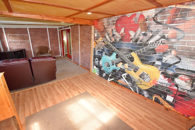 living area with brick wall, wood finished floors, and recessed lighting