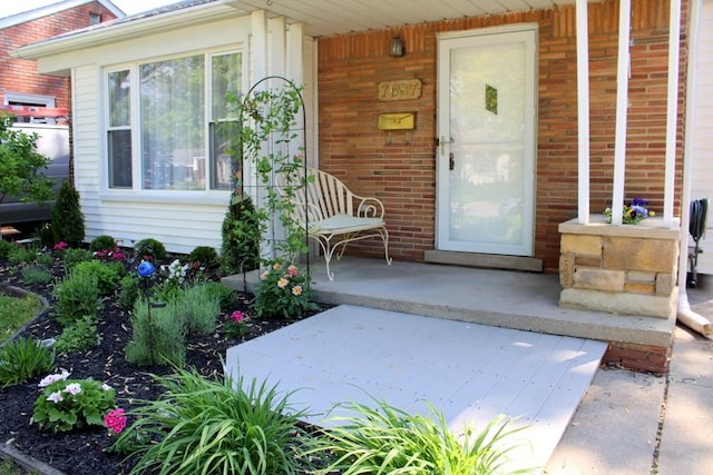 view of exterior entry featuring a porch and brick siding