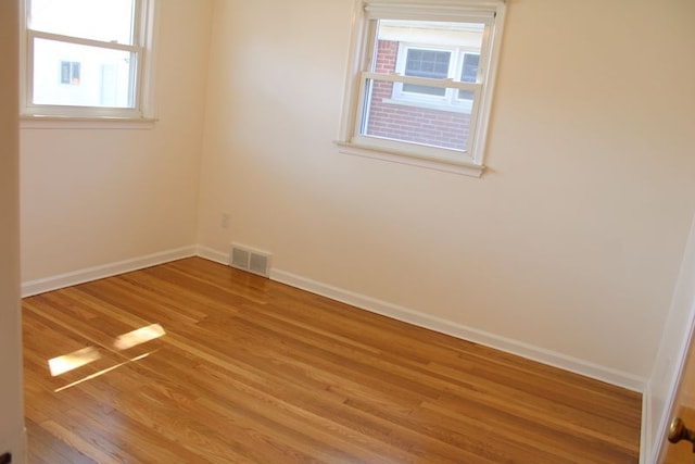 empty room featuring light wood-type flooring, healthy amount of natural light, and baseboards