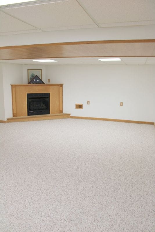 finished below grade area featuring carpet floors, a fireplace, baseboards, and a drop ceiling
