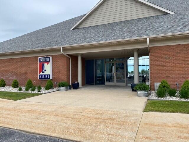 300 S Rath Ave Unit 1, Ludington, MI 49431 - property entrance with roof with shingles, brick siding, concrete driveway, and a carport