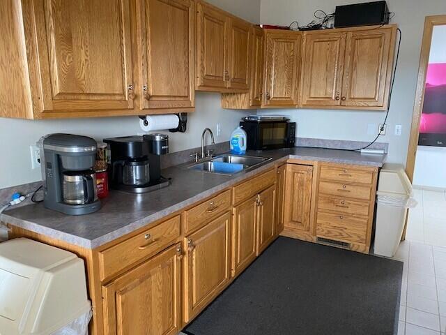 300 S Rath Ave Unit 1, Ludington, MI 49431 - kitchen featuring a sink, tile patterned floors, black microwave, and brown cabinetry