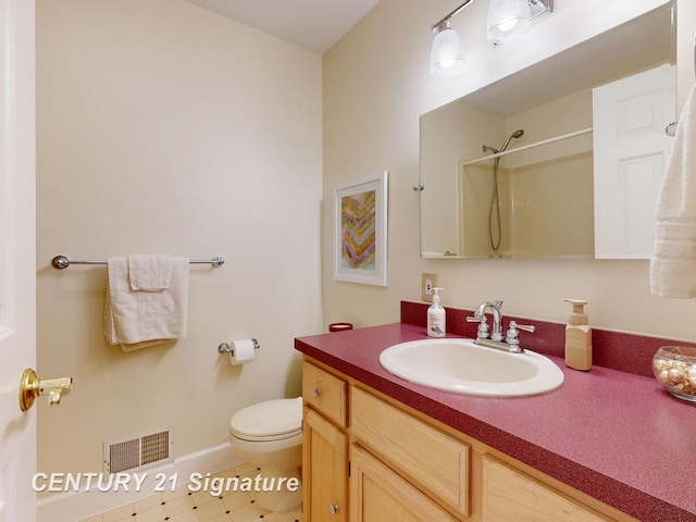 bathroom with vanity, a shower, toilet, and baseboards