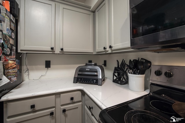 2827 Biddle Ave, Wyandotte, MI 48192 - kitchen with range with electric cooktop, stainless steel microwave, and light stone counters