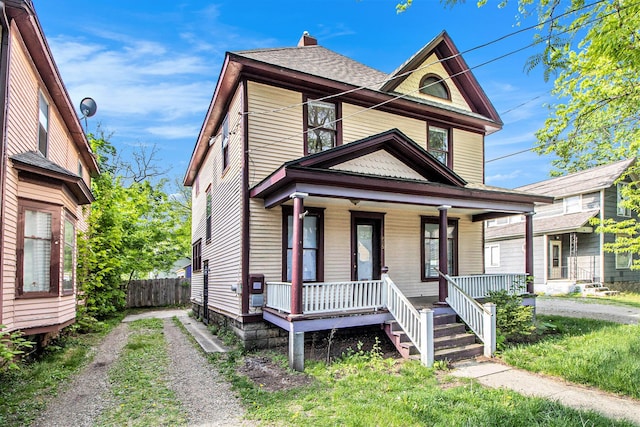 view of front of property with covered porch, roof with shingles, fence, and driveway