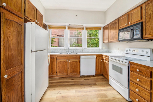 kitchen with white appliances, a sink, light wood-style floors, brown cabinetry, and light countertops