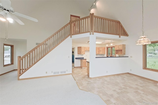 8844 Riverside Dr, Brighton, MI 48116 - unfurnished living room with track lighting, high vaulted ceiling, ceiling fan, and healthy amount of natural light