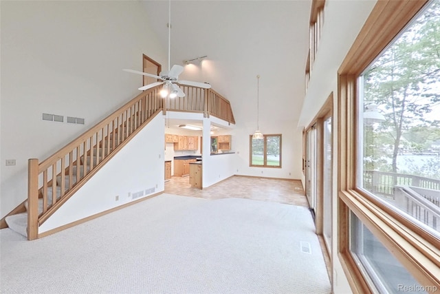 8844 Riverside Dr, Brighton, MI 48116 - unfurnished living room with a high ceiling, light colored carpet, stairway, ceiling fan, and baseboards