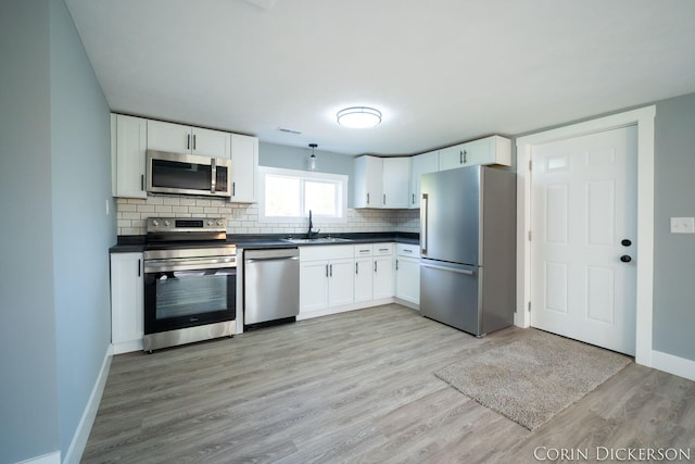 3188 E Stage Rd, Ionia, MI 48846 - kitchen with appliances with stainless steel finishes, a sink, dark countertops, and light wood finished floors