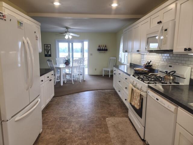 1788 W Beaver Rd, Bitely, MI 49309 - kitchen with white appliances, ceiling fan, dark countertops, white cabinets, and decorative backsplash