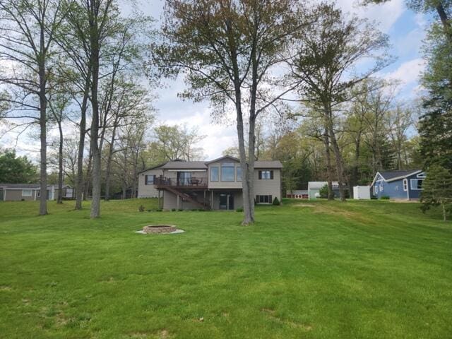 1788 W Beaver Rd, Bitely, MI 49309 - view of grassy yard featuring an outdoor fire pit, a deck, and stairway