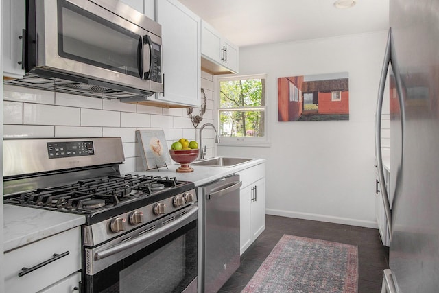 kitchen with stainless steel appliances, a sink, decorative backsplash, and white cabinetry