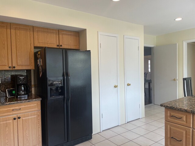 5250 Hardwoods Dr, West Bloomfield, MI 48323 - kitchen featuring black fridge, light tile patterned flooring, tasteful backsplash, dark stone countertops, and brown cabinetry