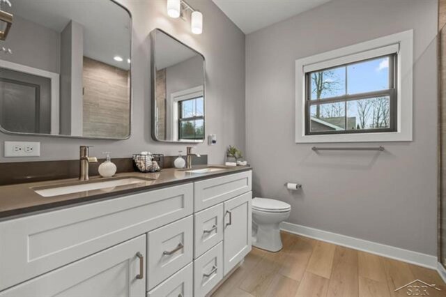 12405 Northway Pkwy, Freeland, MI 48623 - full bath with baseboards, double vanity, wood finished floors, and toilet