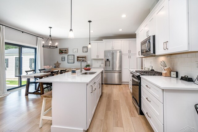 12405 Northway Pkwy, Freeland, MI 48623 - kitchen featuring appliances with stainless steel finishes, a sink, a breakfast bar, decorative backsplash, and light wood finished floors