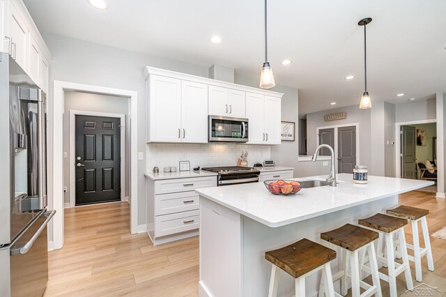12405 Northway Pkwy, Freeland, MI 48623 - kitchen with appliances with stainless steel finishes, light wood-type flooring, a sink, white cabinetry, and decorative backsplash