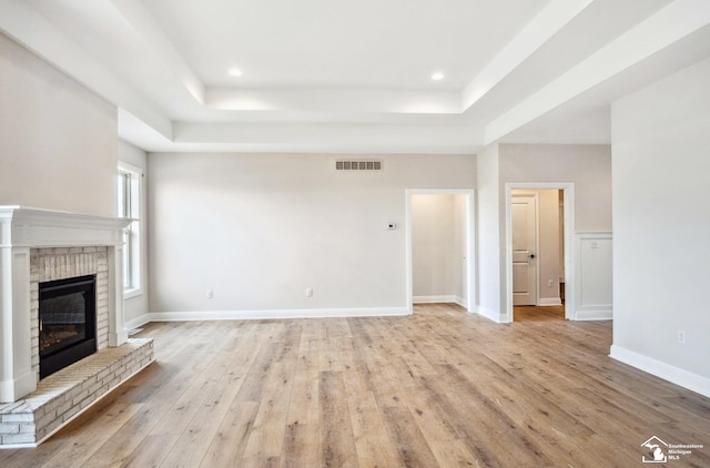 11020 S Custer Rd, Monroe, MI 48161 - unfurnished living room featuring a tray ceiling, a brick fireplace, light wood-style floors, baseboards, and recessed lighting