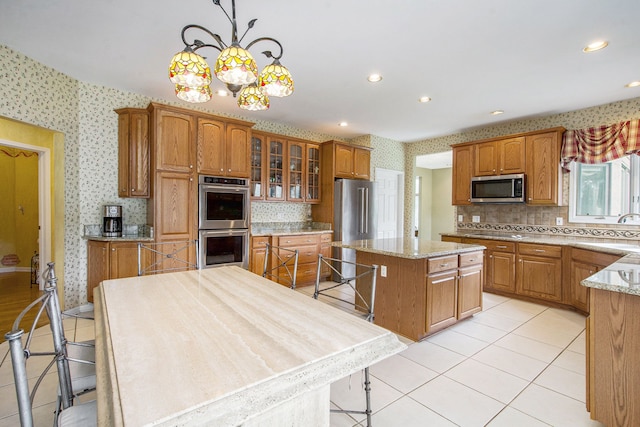 9968 Tuscany Valley Way S, Lyon, MI 48178 - kitchen with stainless steel appliances, light tile patterned floors, backsplash, wallpapered walls, and a chandelier