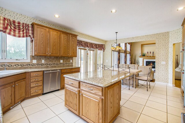 9968 Tuscany Valley Way S, Lyon, MI 48178 - kitchen with stainless steel dishwasher, healthy amount of natural light, light tile patterned flooring, a kitchen island, and wallpapered walls
