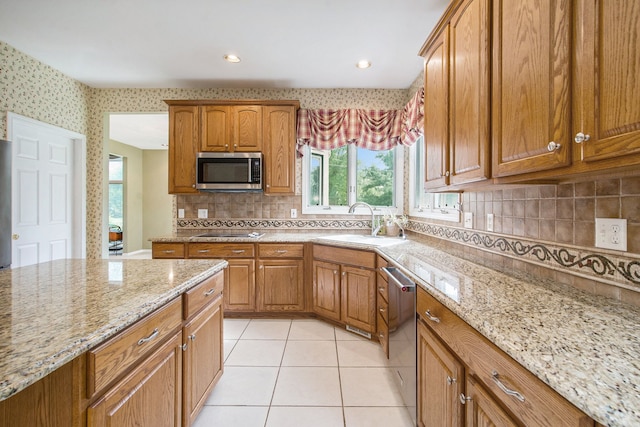 9968 Tuscany Valley Way S, Lyon, MI 48178 - kitchen with appliances with stainless steel finishes, a sink, light stone countertops, decorative backsplash, and brown cabinets