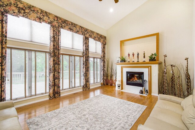 9968 Tuscany Valley Way S, Lyon, MI 48178 - living area with high vaulted ceiling, a tile fireplace, wood finished floors, a ceiling fan, and baseboards