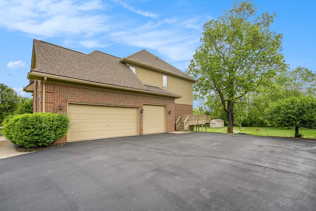 9968 Tuscany Valley Way S, Lyon, MI 48178 - view of property exterior with driveway, brick siding, a garage, and roof with shingles