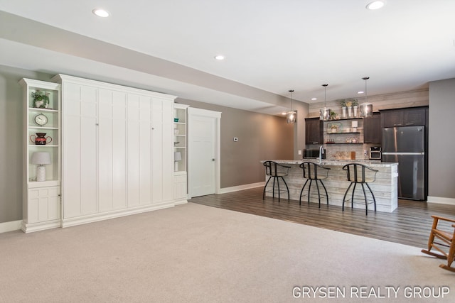 6326 Eaglewood Dr, Hudsonville, MI 49426 - kitchen featuring freestanding refrigerator, open shelves, a breakfast bar, dark brown cabinetry, and baseboards