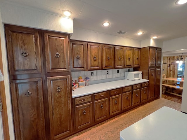 25722 Rainbow Dr, Sturgis, MI 49091 - kitchen featuring white microwave, light wood-style floors, light countertops, recessed lighting, and brown cabinets