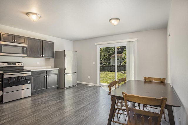 kitchen featuring stainless steel appliances, dark wood finished floors, light countertops, baseboards, and dark brown cabinets